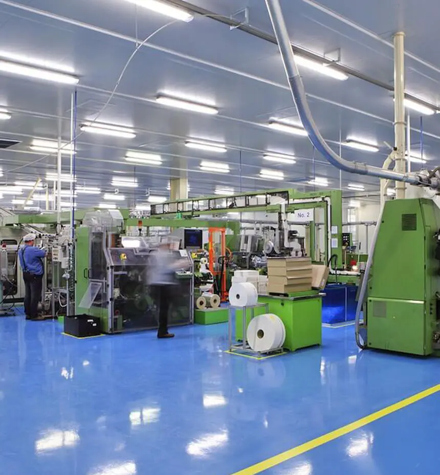 Linear LED fixtures illuminating machinery and work areas in a factory.